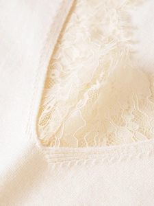 Detailed view of cream wool blend knitwear featuring elegant lace trim on the neckline
