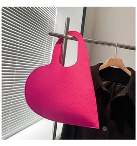 Detail of a bright pink heart-shaped felt handbag with premium stitching and geometry