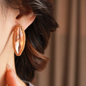 Detailed view of amber oval crystal earrings with intricate gold beaded metal borders