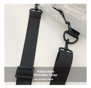 Detail showing the adjustable black woven shoulder strap and matte hook of the nylon bag