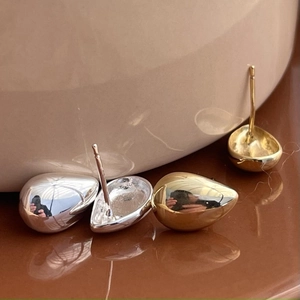 Macro view of gold and silver teardrop stud earrings with a polished metallic finish