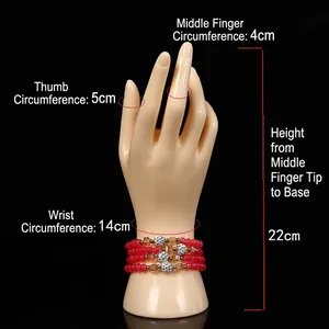 Female plastic hand model for jewelry display featuring red beaded bracelets on black background