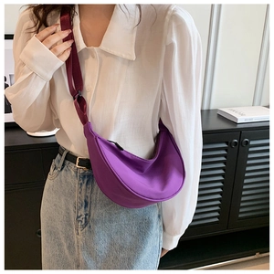 Detail of a purple crescent nylon crossbody bag worn by a model in casual style
