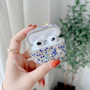 Sparkling silver AirPods Pro case with blue rhinestones held in hand with plant background