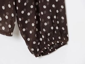 Close-up of elastic cuffs on a brown chiffon shirt with white polka dot patterns