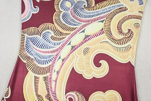 Detail of burgundy jumpsuit featuring vintage paisley pattern on smooth fabric