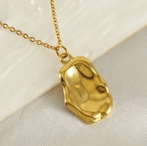 Vue macro d'un collier doré 18K avec pendentif rectangulaire texturé sur tissu blanc