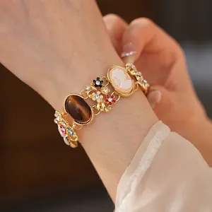 Vintage gold enamel bracelet featuring cameo charm, cat-eye stone, and colorful flowers