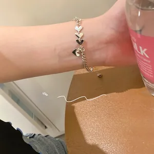 Primer plano de la pulsera plateada con eslabones de corazón y cadena ajustable en la muñeca