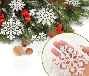 Close-up of white glitter snowflake ornament with intricate hollow design and hand for scale