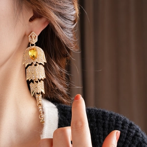 Detailed view of long vintage gold earrings with white pearls and a yellow water-drop gem