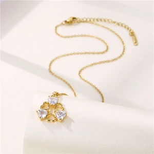 Collier cœur minimaliste doré avec zircons et pendentifs cœurs évidés sur support blanc