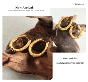 Macro shot of U-shaped gold-plated stainless steel earrings on a rustic wood background