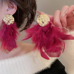 Detailed close-up of gold hammered metal stud with long fuchsia feather fringe tassel earrings
