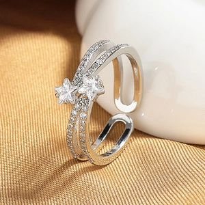 Detalle de anillo doble plateado con estrellas de circón brillante sobre seda dorada