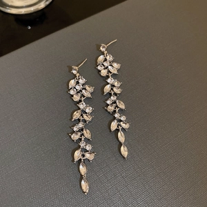 Close-up of silver tassel earrings with marquise-cut zircons in a leaf-like design