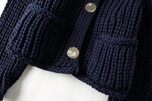 Détails d'un gilet en grosse maille bleu marine avec boutons argentés et texture