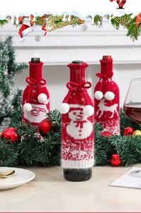 Close-up of Santa, Snowman and Reindeer knitted wine bottle covers with white pompoms