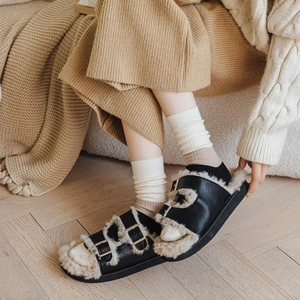 Detail of black faux leather sandals with beige plush lining and golden double buckles