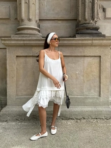 Détail d'une robe blanche à fines bretelles avec dentelle et ourlet multicouche fluide