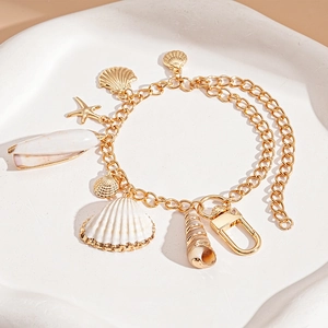 Golden ocean theme charm bracelet featuring white seashells, starfish and conch pendants