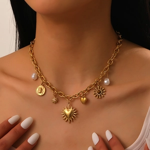 Close-up of gold chunky chain necklace with pearl, heart and insect charms on model