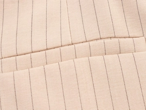 Détail du tissu tissé à rayures kaki avec coutures précises sur le bord de poche