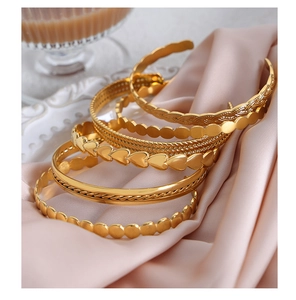 Close-up of gold-plated hip hop bracelets on satin featuring heart and woven patterns