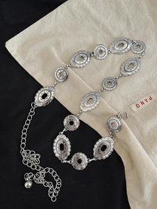 Detailaufnahme der silbernen Metall-Taillenkette mit gravierten Blättern auf Stoff