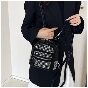Primer plano de una mini mochila negra con pedrería plateada en una modelo femenina