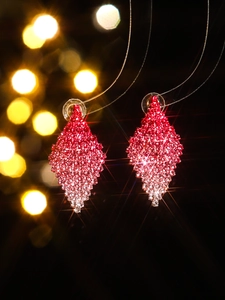 Macro shot of geometric diamond earrings with pink gradient crystals on black background