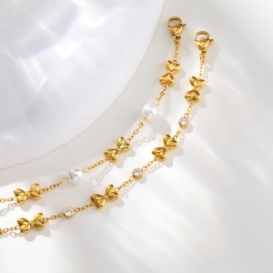 Detail of gold girls bracelet with butterfly bow, faux pearls and lobster clasp