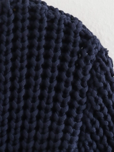Macro detail of navy blue chunky knit fabric with thick V-shaped woven stitch pattern