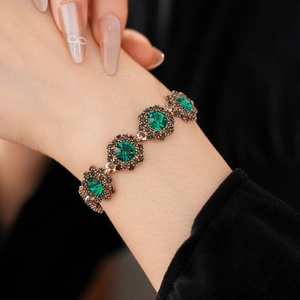 Detailed close-up of a vintage emerald flower bracelet with antique bronze gold finish