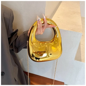 Close-up of golden acrylic handbag with sleek streamline design and fine chain strap