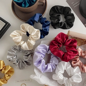 Macro shot of assorted satin silk scrunchies with elegant glossy texture and vivid colors