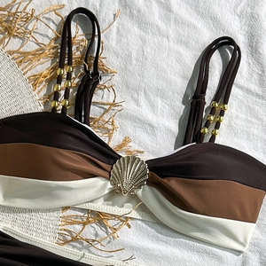 Detail of bikini top with tricolor stripes, golden shell charm and beaded straps