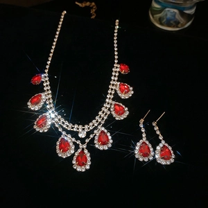 Sparkling starburst lighting on gold necklace and red teardrop earrings set