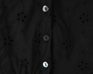 Gros plan sur tissu en coton noir avec broderie florale et détails de boutons dorés
