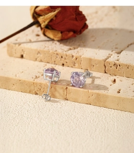 Detailed view of S925 silver lavender zircon studs on a textured stone with a dry rose