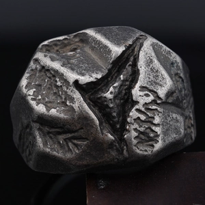 Macro shot of silver textured stainless steel ring with natural meteorite surface details