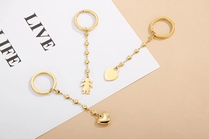 Detail of three-piece golden stainless steel keychains with heart and figure charms