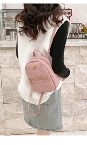 Detailed back view of a pink mini quilted backpack on a model in a cafe setting