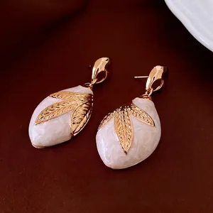 Vintage gold leaf drop earrings with white marble resin inlay on dark background