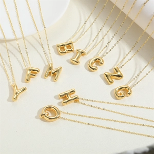 Detailed close-up of 3D bubble initial letter necklaces in 14K gold plated finish