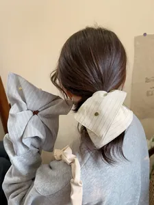 Detail showing oversized striped bow hair scrunchies with vintage metal stud accents