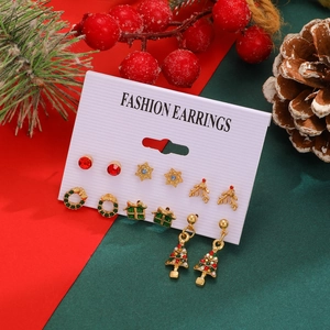 Close-up of a Christmas earring set with Santa, reindeer, and tree designs on a festive card