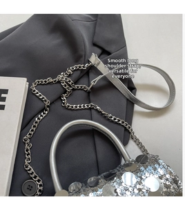 Detail of silver sequin handbag with metal chain strap on a grey suit jacket