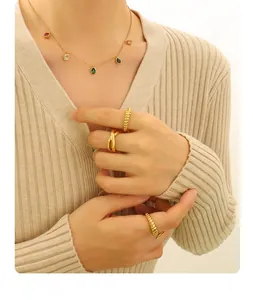 Close-up of gold necklace with colorful teardrop stones and textured rings on a model