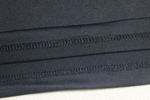 Detail of black knit fabric showing high-quality double-needle stitching and texture